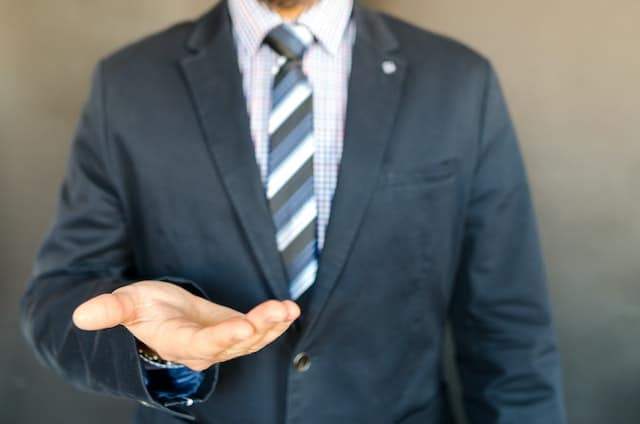 person in a suit holding out their hand