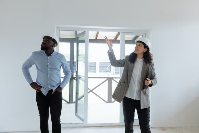 two people in hard hats looking at a house