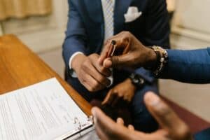 two people in suits passing over a pen while signing a contract