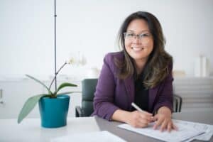 person in a purple suit signing papers in an office
