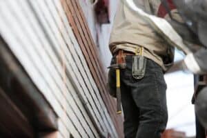 person on the side of house with tools on their belt