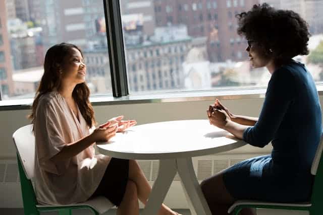 two-women-sitting-at-a-table-engaged-in-a-conversation