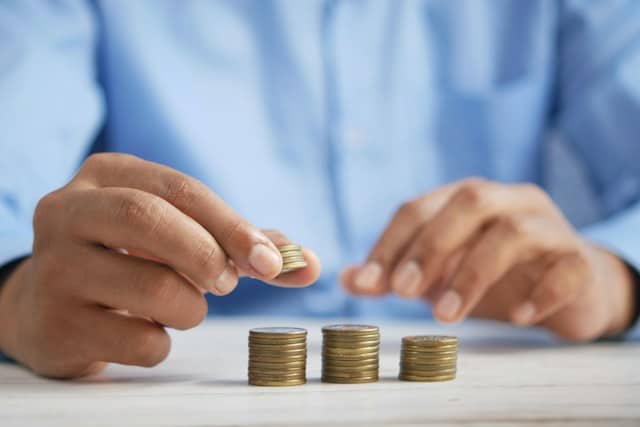 a-person-stacking-coins-on-a-table-wearing-a-blue-shirt
